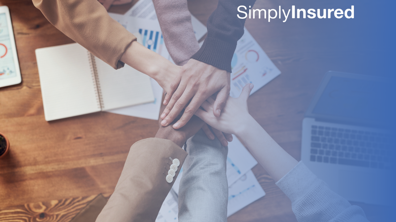 Teamwork - six individuals placing their hands together in camaraderie 