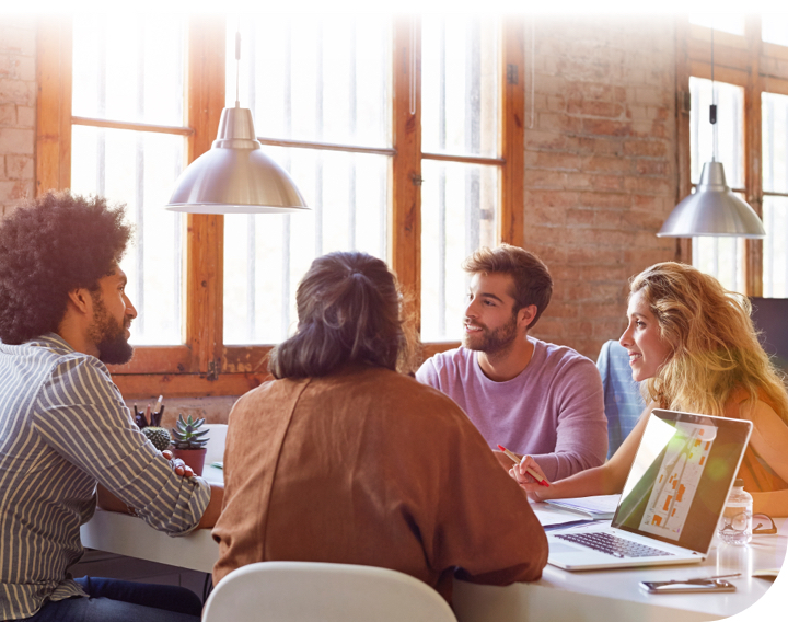 Four employees collaborating at sunlit table